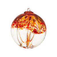 A clear glass orb with red, orange and pink swirled on the top half with red webbing pulled from bottom to top on a transparent background. 