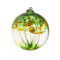 A clear glass orb with green, amber, red and orange swirled on the top half with green webbing pulled from bottom to top on a transparent background.