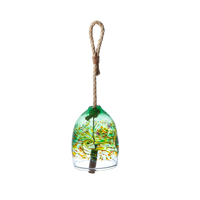 A clear glass bell with green, opaque lime, orange and purple glass swirled across the middle. A wooden toggle and rope are pulled through the middle on a transparent background