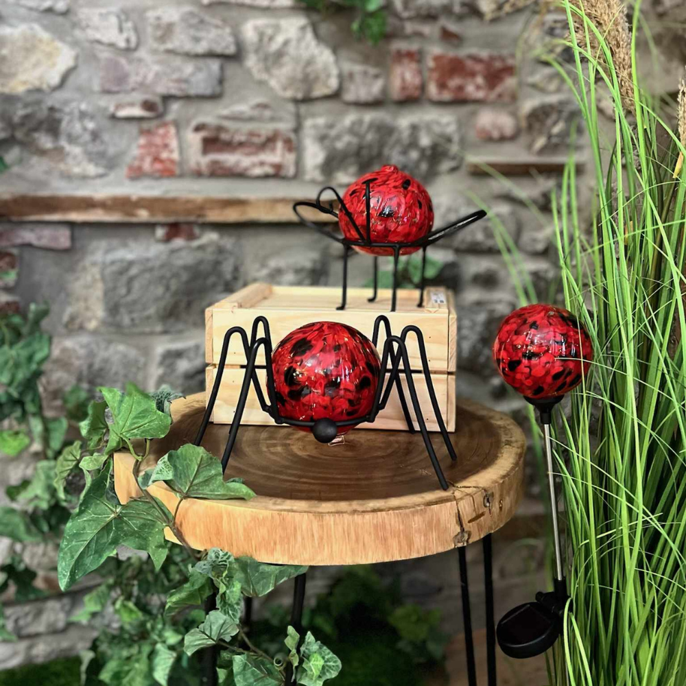 Spider Garden Holder with Ladybird Red Nature's Whimsy Orb and Insect Garden Holder with Nature's Whimsy Oil Lamp and Ladybird Red Nature's Whimsy Solar Light. All in a nature scene. 
