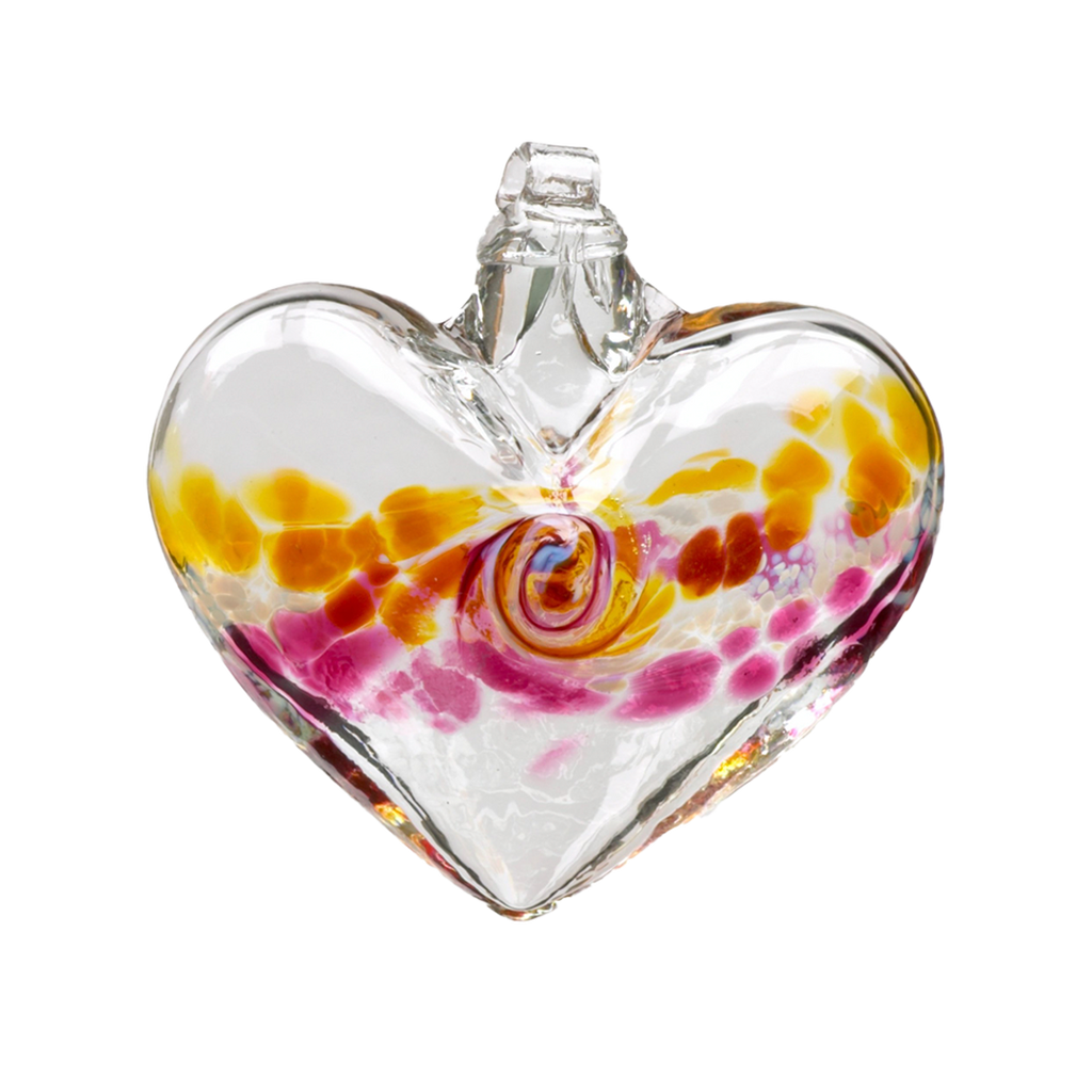 Glass heart with amber on top, white swirled across the middle and pink on the bottom on a transparent background.