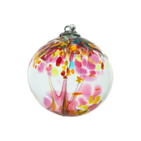 Clear glass orb with pink glass pulled through the middle and yellow, red, pink, orange and blue glass bits on a transparent background. 