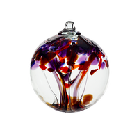 Clear glass orb with clear and purple glass pulled through the middle and red, dark purple, amethyst and brown bits on top on a transparent background.