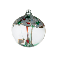 Clear glass orb with red and green glass pulled through the middle and white, red, green and gold glitter glass bits on top on a transparent background.