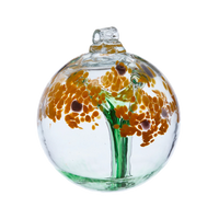 Clear glass orb with a green stem pulled from bottom to top to a canopy of yellow opaque glass blossoms and brown centres on a transparent background.